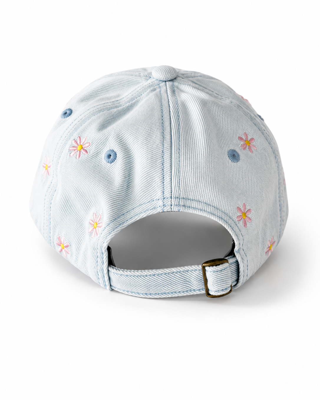 Back view of the light-wash flower-embroidered cap, showing the curved crown and the adjustable strap clipped into its brass buckle.
