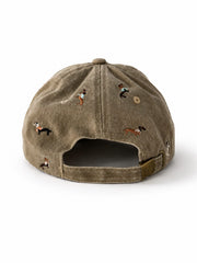 Beige denim baseball cap embroidered with colourful dachshund dogs, front view on a white background.