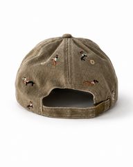 Back view of the beige dachshund-embroidered cap, showing the curved crown and the adjustable strap clipped into its brass buckle.