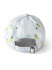 Light-wash denim baseball cap embroidered with small yellow lemons, front view on a white background.