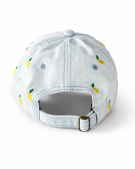 Back view of the light-wash lemon-embroidered cap, showing the curved crown and the adjustable strap clipped into its brass buckle.