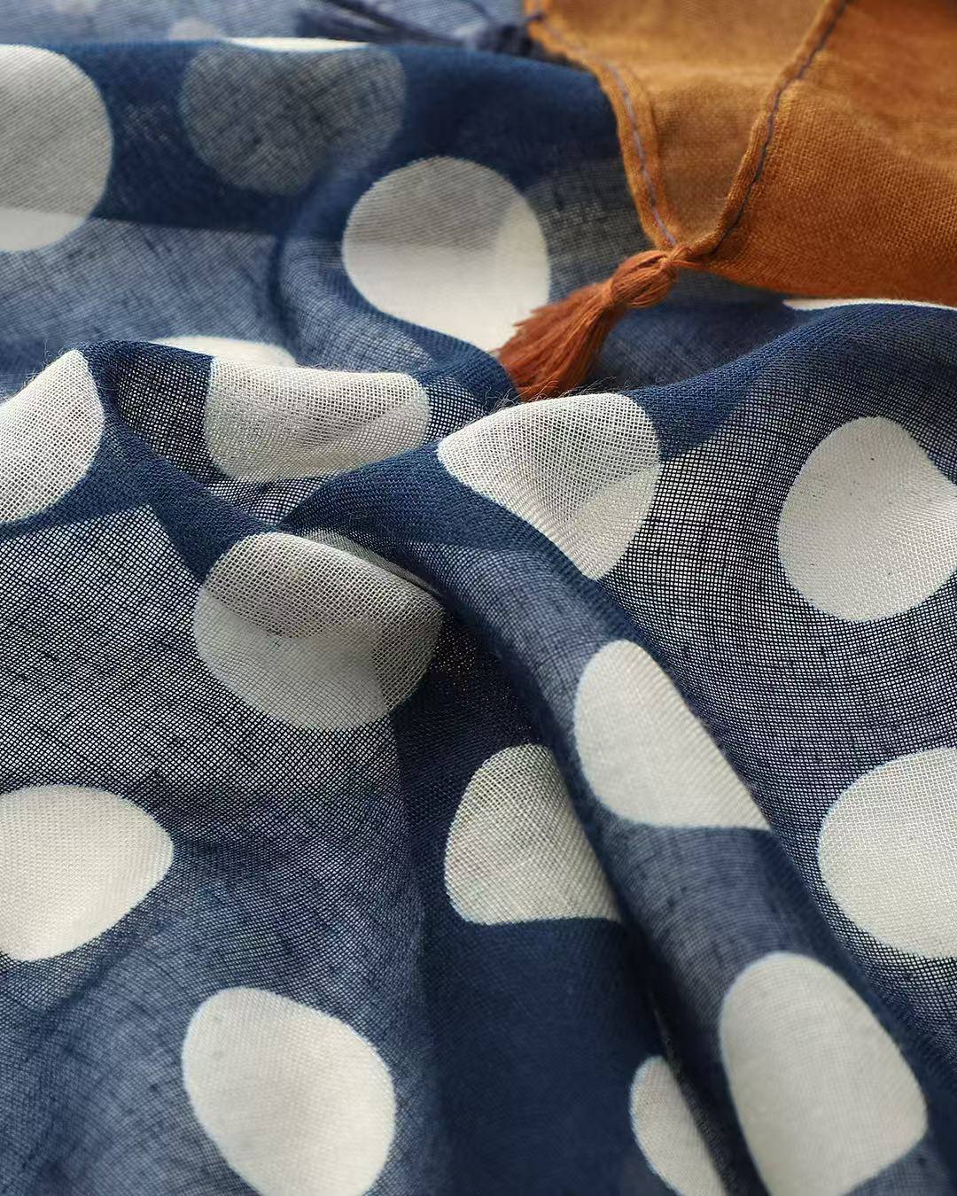 Close-up of navy polka dot panel on colourblock scarf with rust tassel