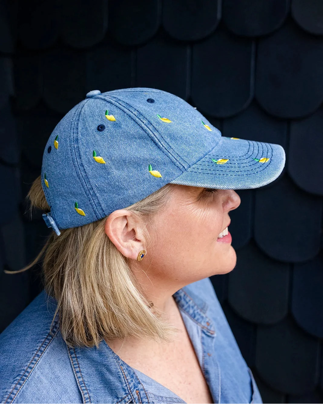 Mid-wash denim baseball cap embroidered with small yellow lemons, front view on a white background.