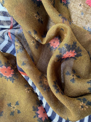 Lightweight scarf with a coral floral print on olive green, a border of rust, navy and navy and white stripes, and coral and tan tassels
