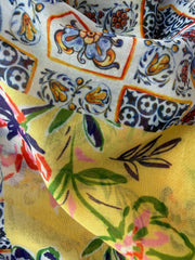 Lightweight scarf with a bright tropical floral and patterned print in yellow, blue, pink and green on white, finished with yellow tassels