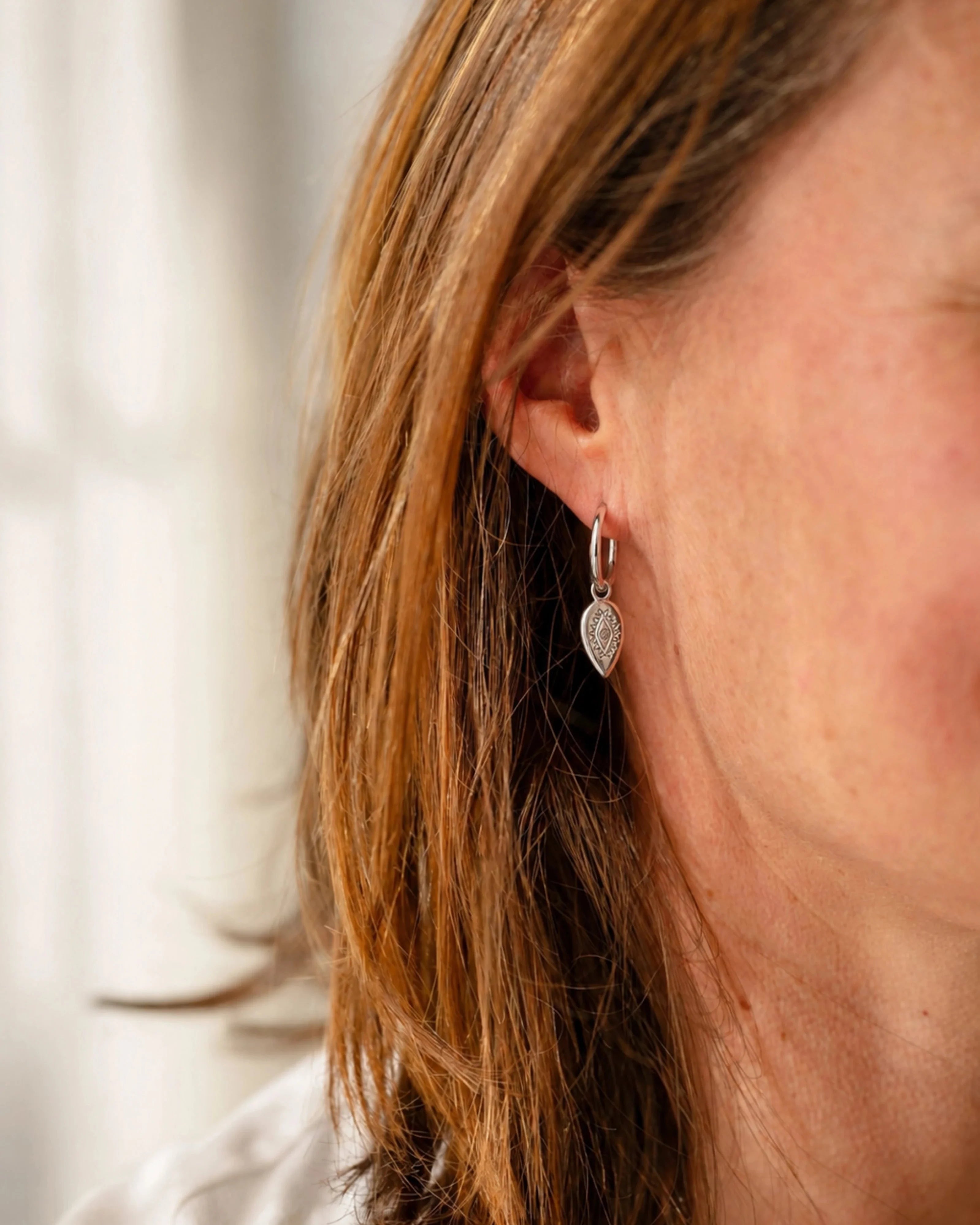 Woman wearing silver Uma marquise dangle hoop earrings