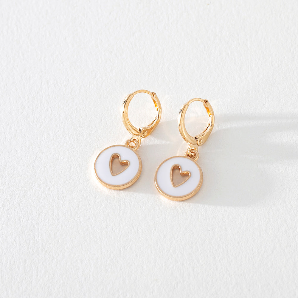 White enamel gold hoop earring with heart cutout detail on white background