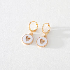 White enamel gold hoop earring with heart cutout detail on white background