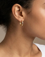 Woman wearing gold hoop earrings with multi coloured crystals