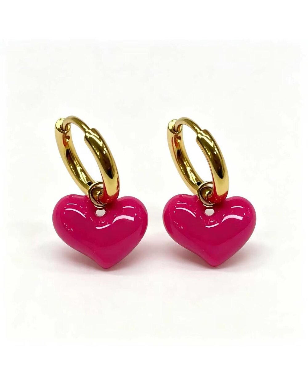 Gold hoop earrings with a pink enamel heart charm dangle
