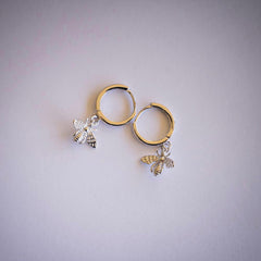 Silver hoop earrings with bee dangle on white background