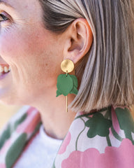Close-up of a person wearing green earrings with floral patterned clothing.