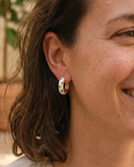 Woman wearing white enamel gold hoop earrings with blue flower pattern